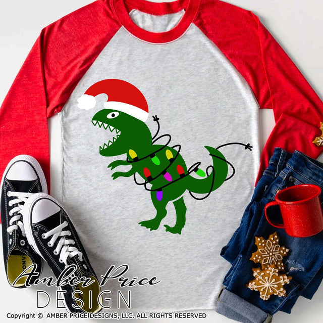 Dinosaur with Christmas lights SVG PNG DXF | Kid's Christmas shirt SVG | Christmas T-Rex SVG SVG Amber Price Design 